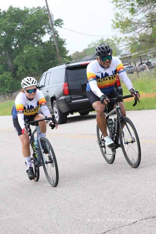 Brightly dressed cyclists riding on a suburban road during a Bluebonnet Express event.