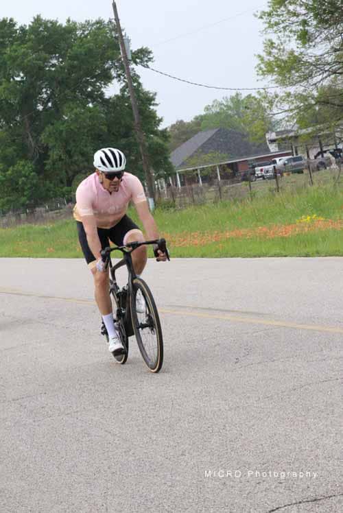 Bright cyclist wearing pink jersey riding on rural road | Bluebonnet Express bike ride event.