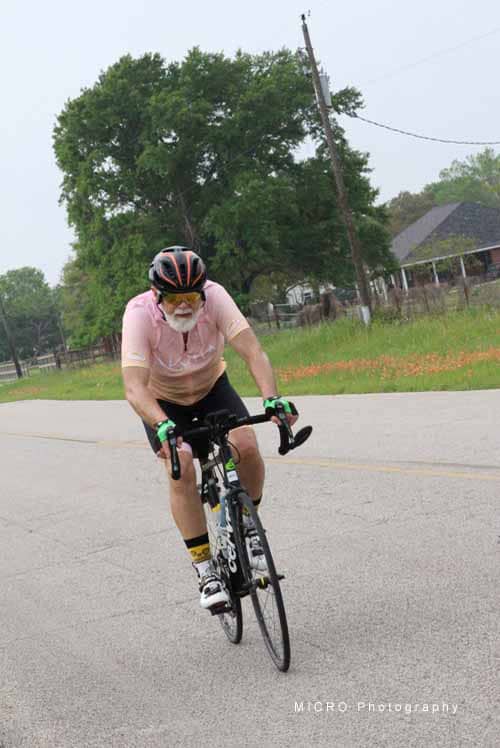 1. Elderly man cycling on rural road during daytime, wearing helmet and sunglasses.