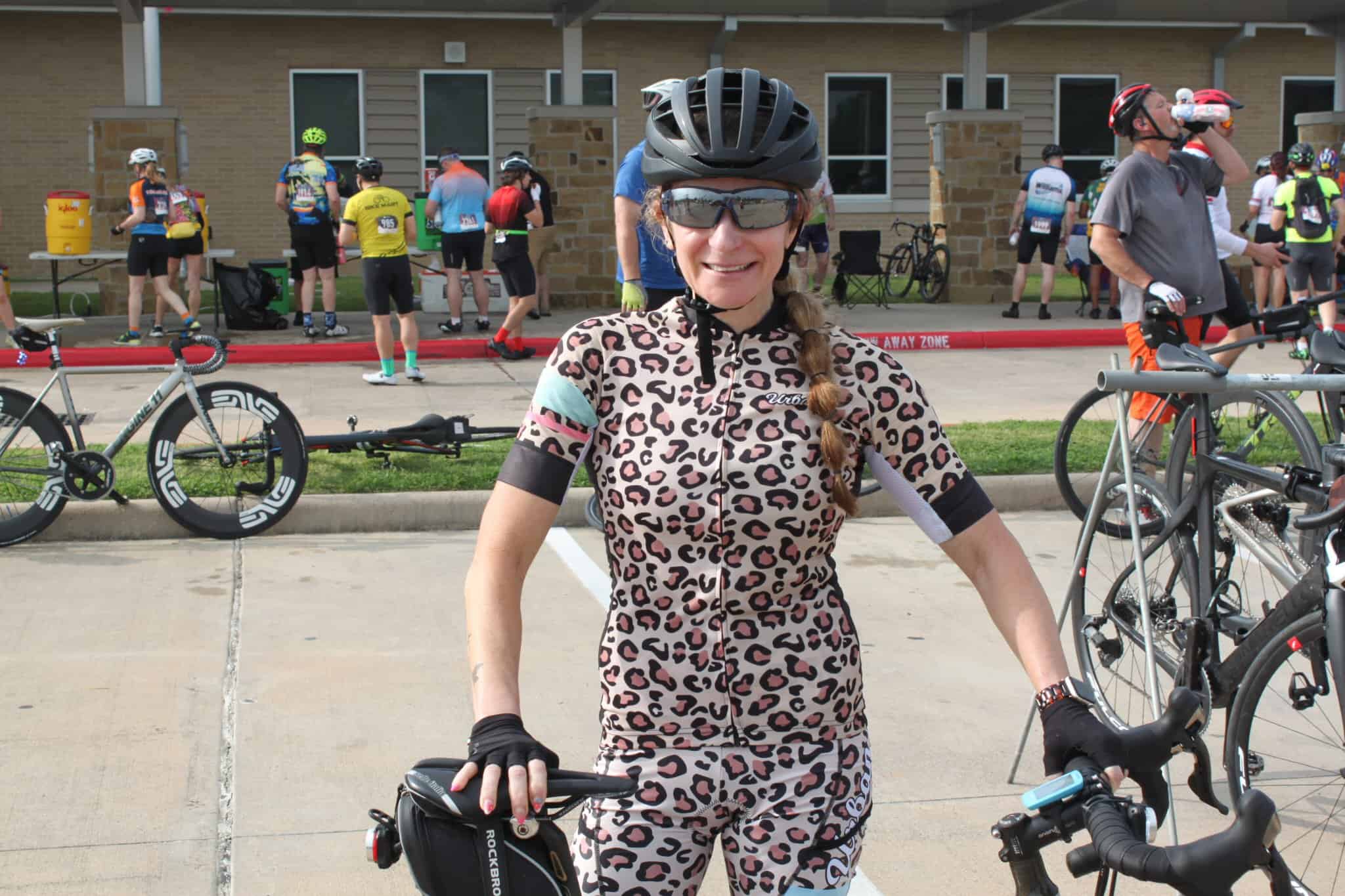 Bright female cyclist smiling at Bluebonnet Express event, wearing leopard print cycling outfit and helmet.