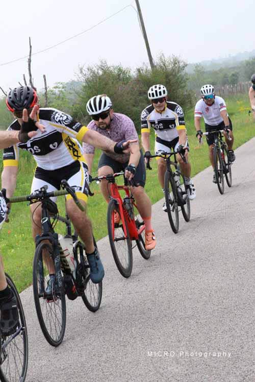 Bright group of cyclists riding on scenic country road during Bluebonnet Express event, promoting outdoor fitness and cycling community.