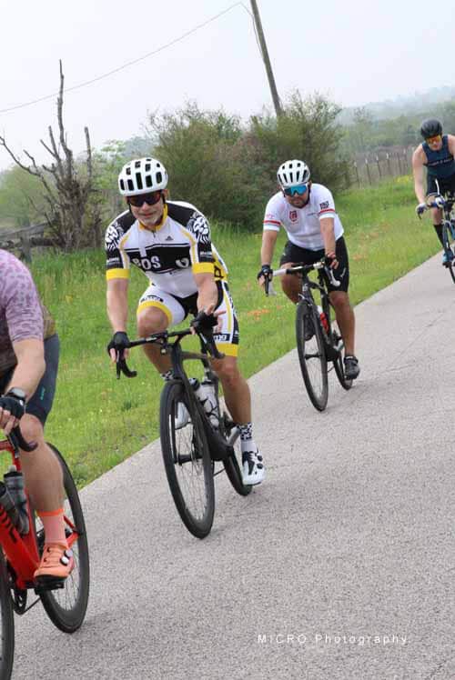 Bright yellow and white cyclist with helmet riding along scenic outdoor trail in Bluebonnet Express event.
