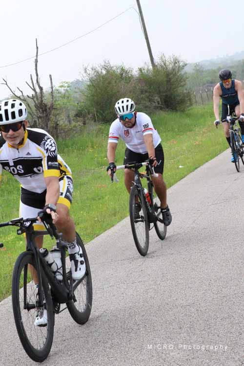 High-performance cyclists riding on a scenic rural road during the Bluebonnet Express event.