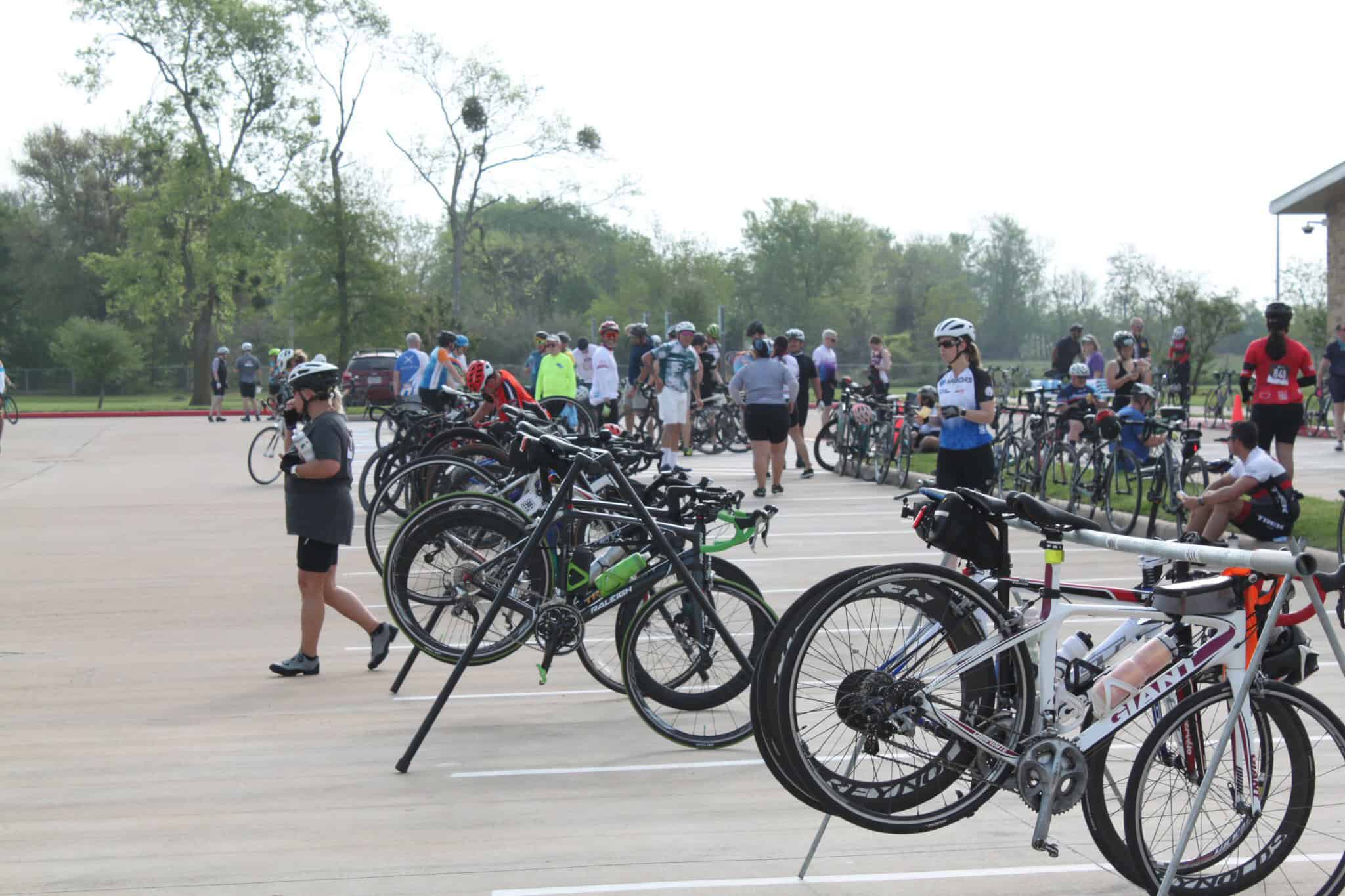Bicycle parking at Bluebonnet Express cycling event with bikers and spectators.