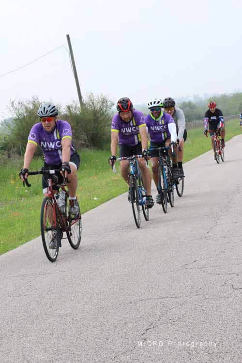 Riders cycling on scenic road during Bluebonnet Express charity event, supporting wellness and community.