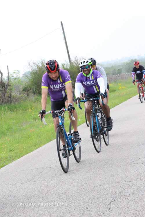Brightly colored cyclists riding on a scenic rural bike path during daytime.