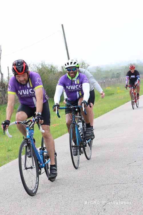 Brightly dressed cyclists enjoying Bluebonnet Express cycling event on a scenic rural road.