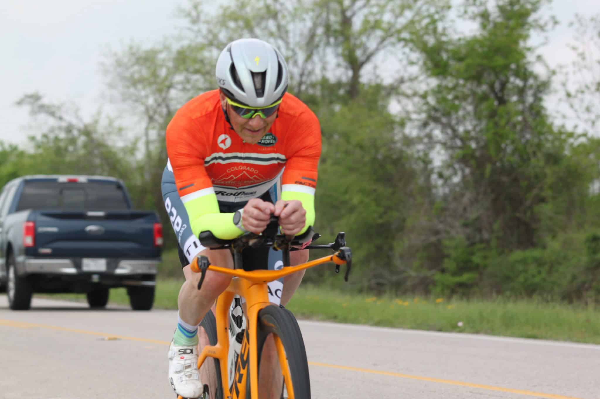 Bright orange cyclist jersey with Colorado design on a road bike during Bluebonnet Express cycling event.