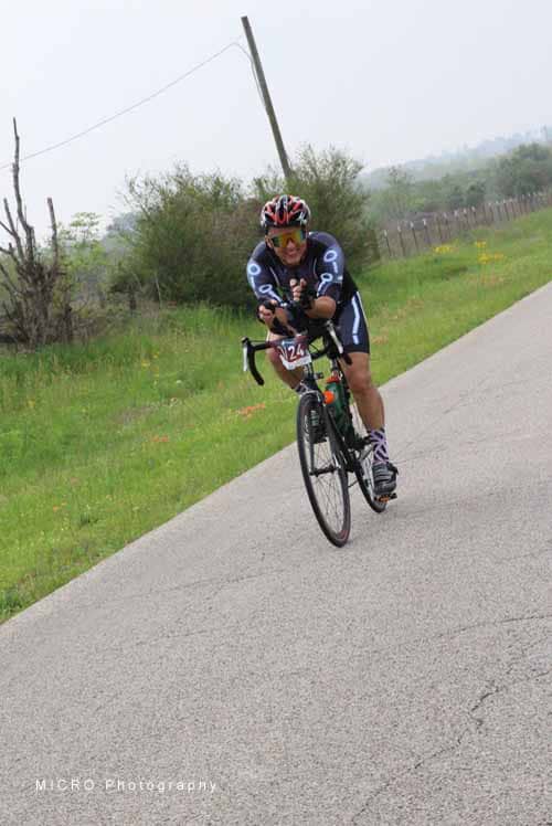 Vibrant cyclist riding on scenic rural road during Bluebonnet Express event.