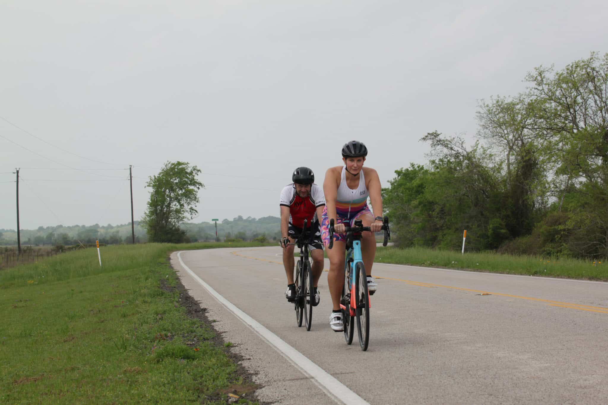 1. Female cyclists riding on rural road with open sky, eco-friendly transport, Bluebonnet Express.