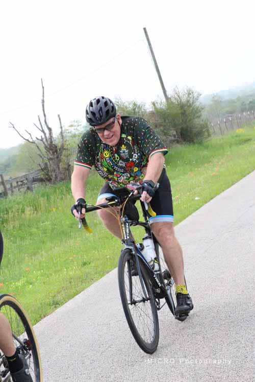 Bicyclist wearing colorful jersey riding on a rural road during the Bluebonnet Express event.