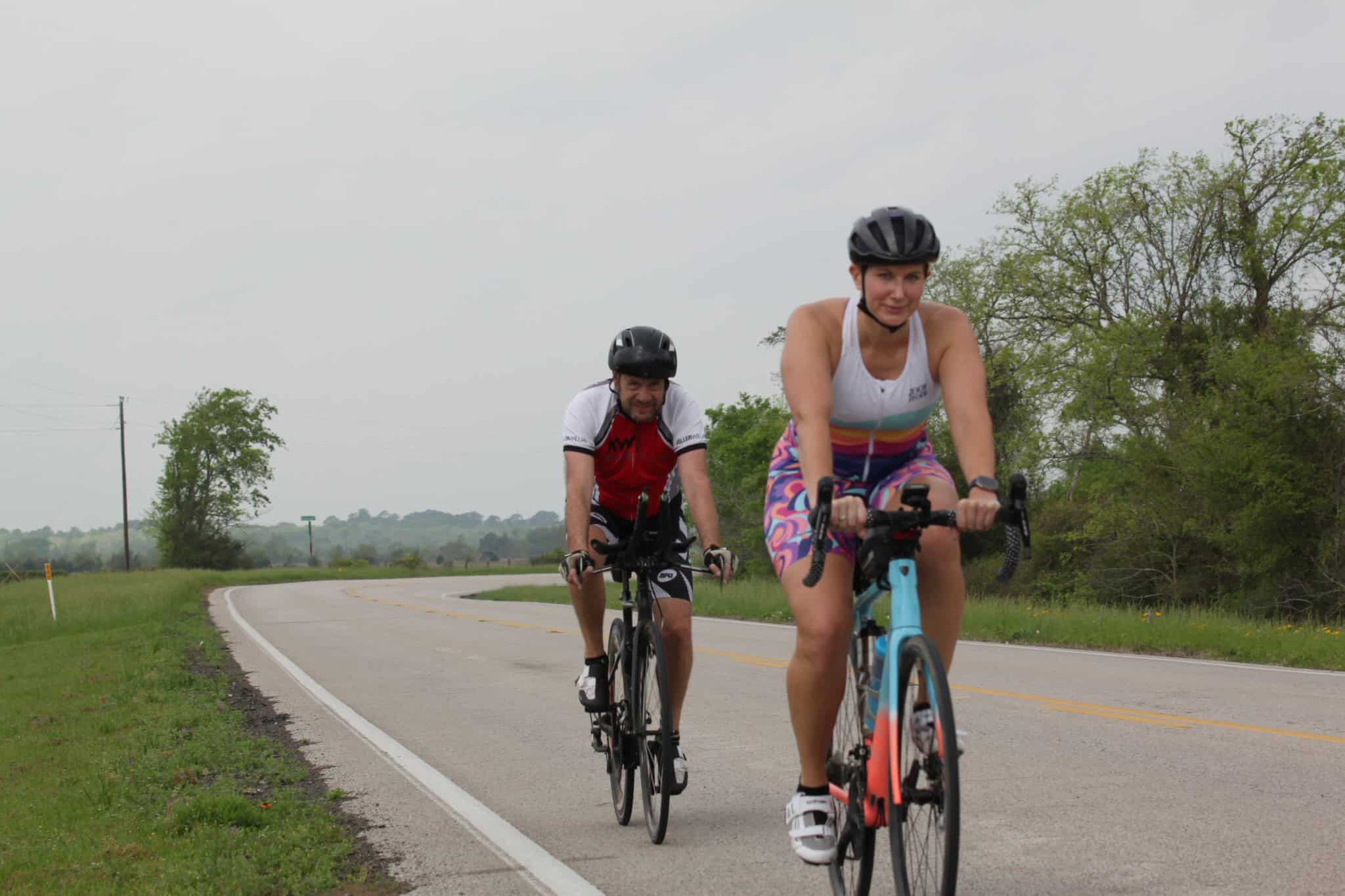 Vibrant cyclists enjoying a scenic ride on a rural road with lush greenery, promoting outdoor cycling adventures.