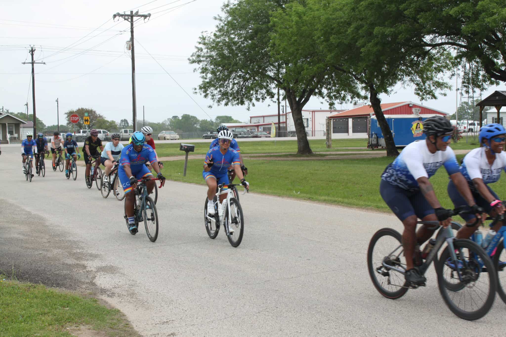 Bicycle riders participating in a group ride event on a suburban street, promoting cycling and community activity.