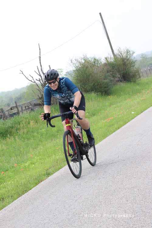Vivid cyclist riding on scenic bike trail during daytime, wearing helmet and sporty attire, promoting outdoor cycling activity.