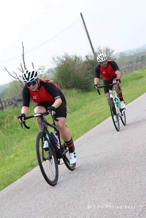 Efficient cycling by two riders during Bluebonnet Express event on a scenic rural road.