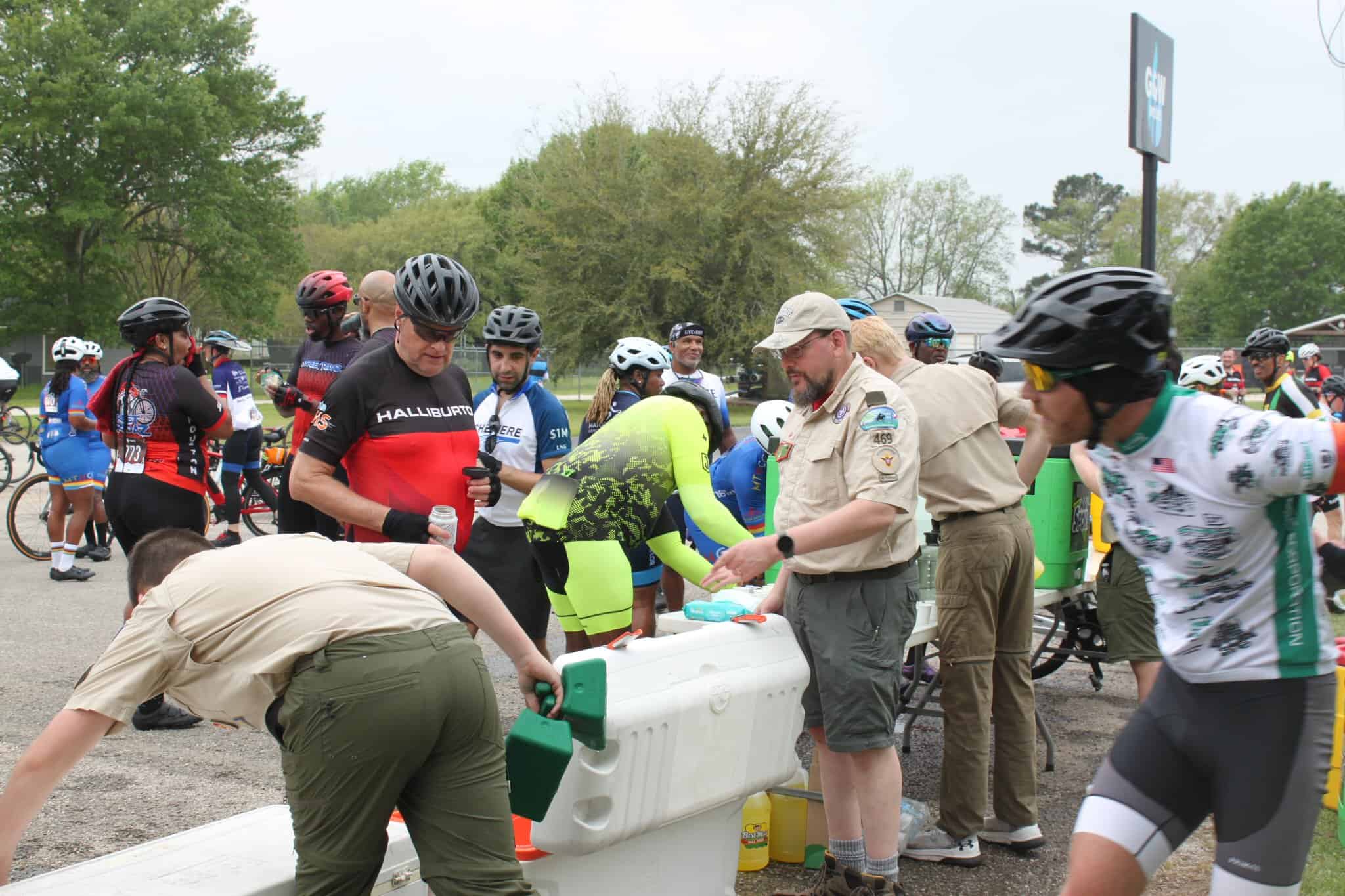 Vibrant group of cyclists at Bluebonnet Express event receiving water and support, showcasing community spirit and cycling culture.