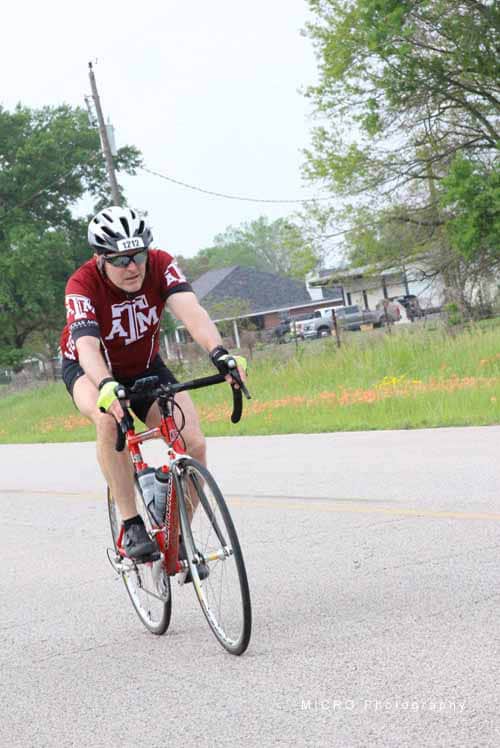High-performance cyclist riding on rural road during Bluebonnet Express event.
