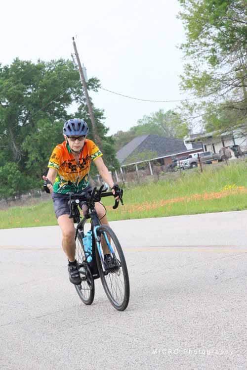 Bike rider in colorful cycling jersey on Bluebonnet Express trail, Texas scenic biking path.