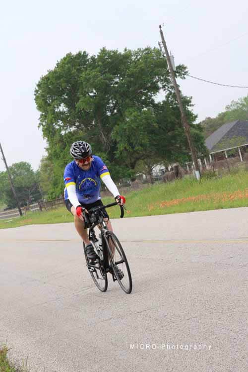 Rider cycling on open road in Bluebonnet Express event, enjoying scenic Texas countryside.