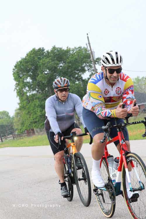Brightly colored cyclists enjoying a ride on a scenic road during daytime.