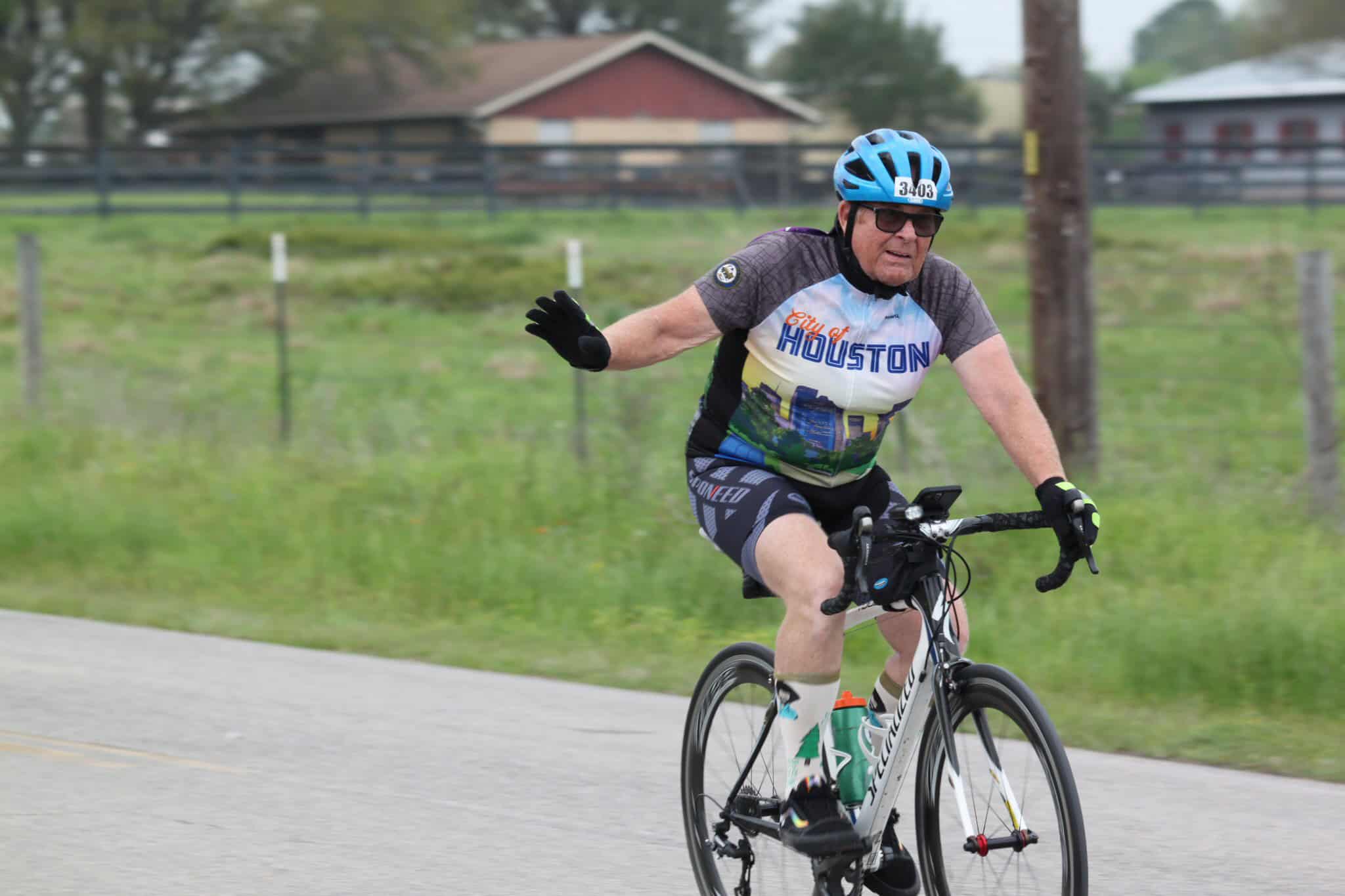 Cyclist wearing Houston city jersey riding bike on open road during bike race.