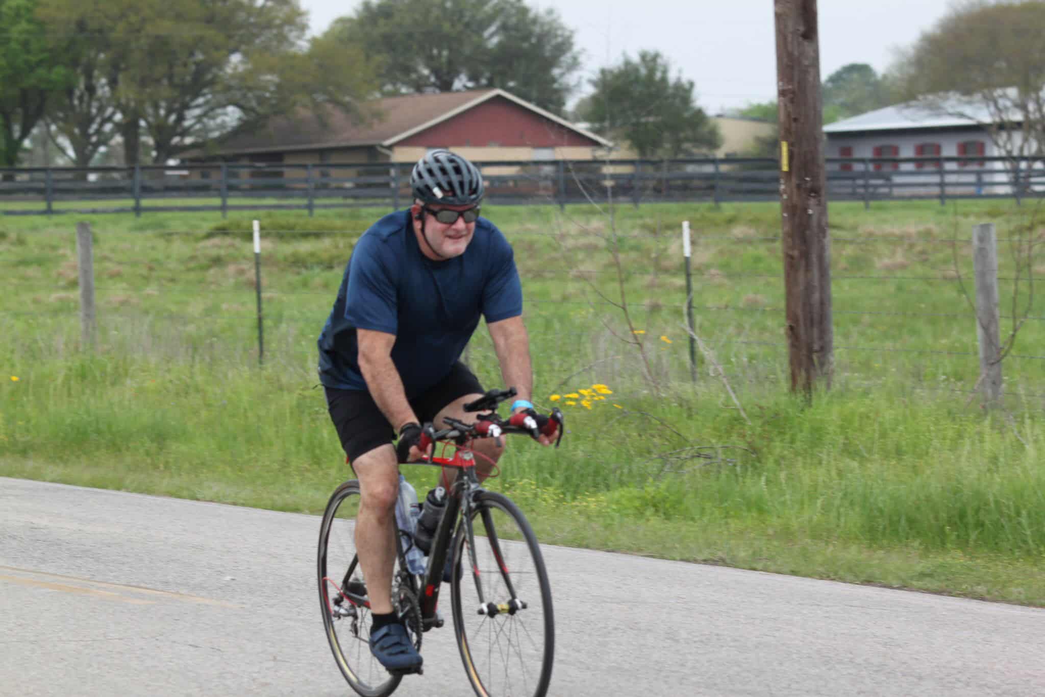 Cyclist riding on scenic rural road during daytime, promoting Bluebonnet Express bike transportation.