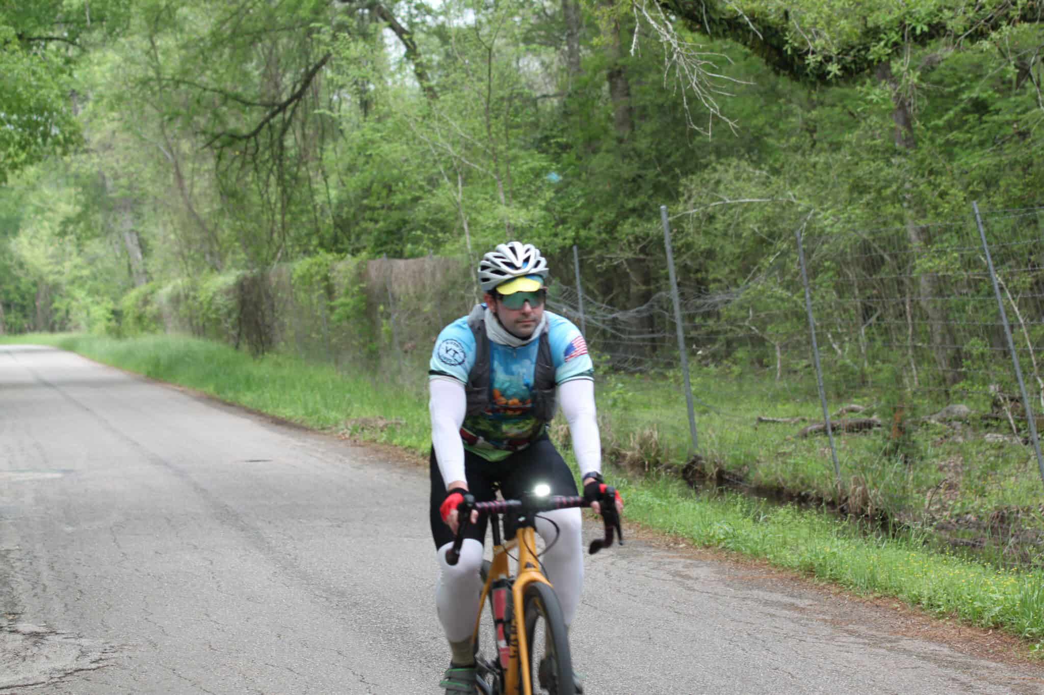 Vibrant cyclist riding through lush green forest on Bluebonnet Express bike route.