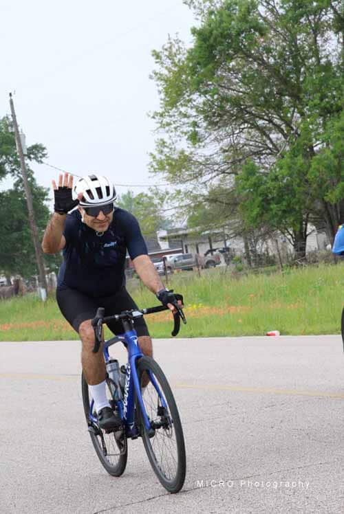 Cyclist waving during Bluebonnet Express ride on a sunny day.
