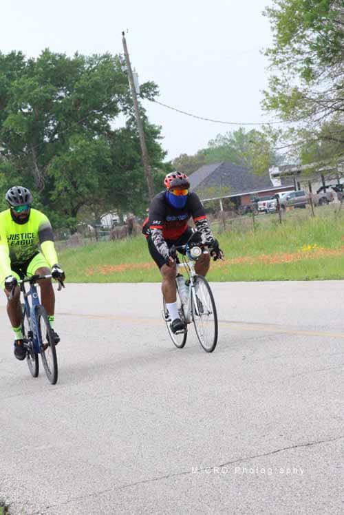 Brightly dressed cyclists riding on a rural road, promoting eco-friendly transportation and community health.
