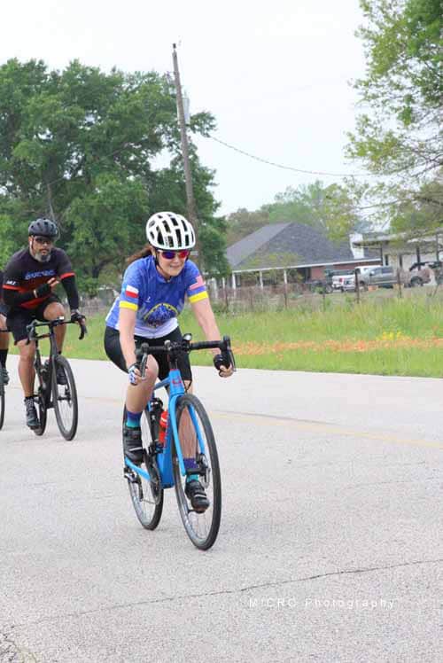 Bright female cyclist riding a blue bike during Bluebonnet Express event in Texas, promoting cycling and outdoor activity.