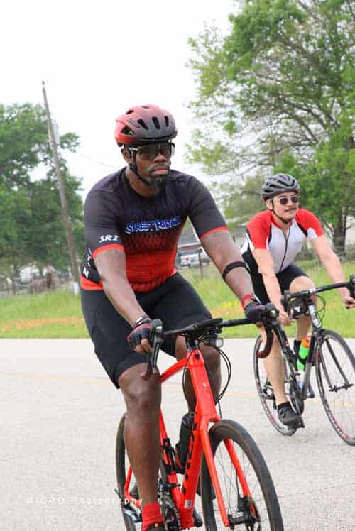High-performance cyclist on Bluebonnet Express bike ride, wearing safety gear and enjoying outdoor cycling.