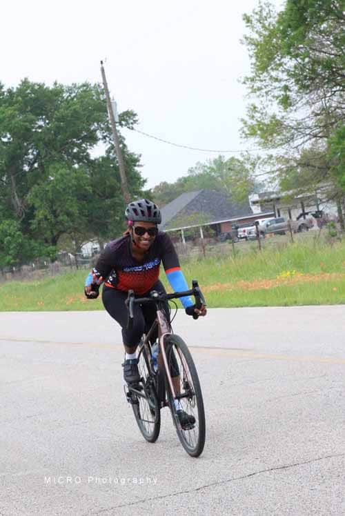Bright cyclist riding a bike on a paved road outdoors for Bluebonnet Express event.