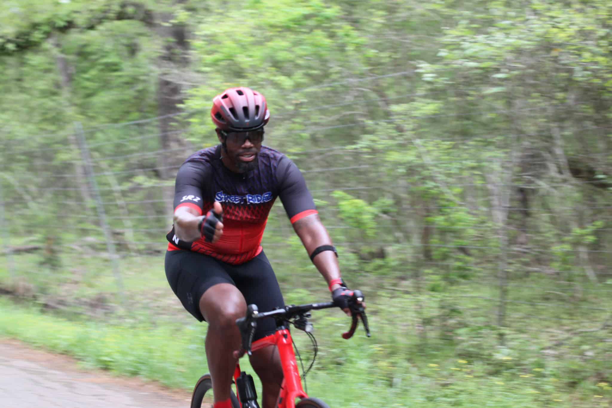 Vibrant cyclist on Bluebonnet Express trail surrounded by lush green woods.