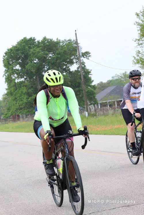 1. Female cyclist wearing bright green jacket and helmet riding on rural road.