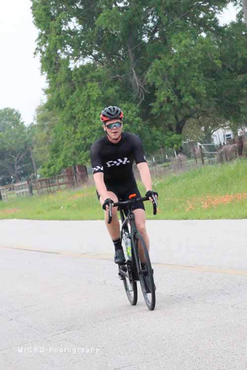 High-performance cyclist riding on rural road during daytime.