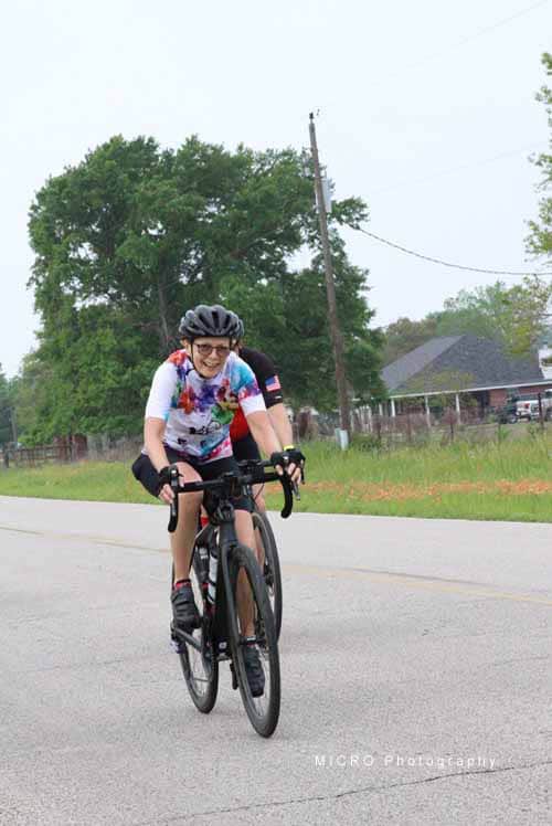 Bright smiling cyclist riding on a rural road during daytime for Bluebonnet Express event.