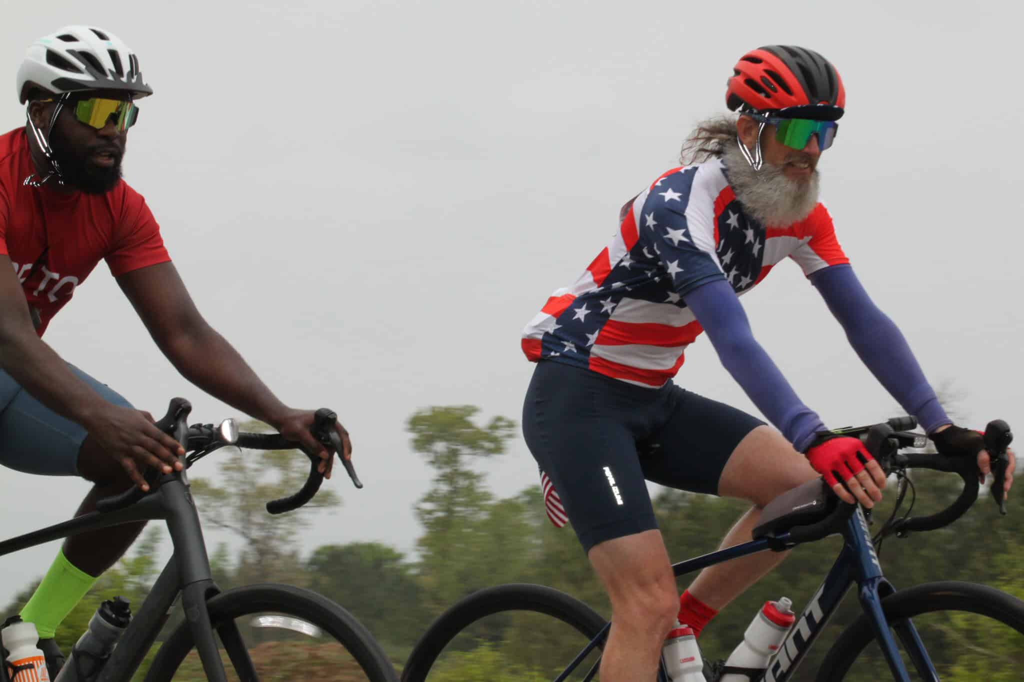 Vibrant cyclists enjoying a ride outdoors with patriotic jerseys and safety gear on a cloudy day.