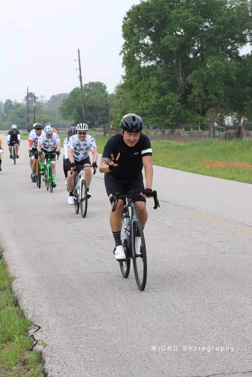 Bright group of cyclists riding on rural road during Bluebonnet Express event in Texas.