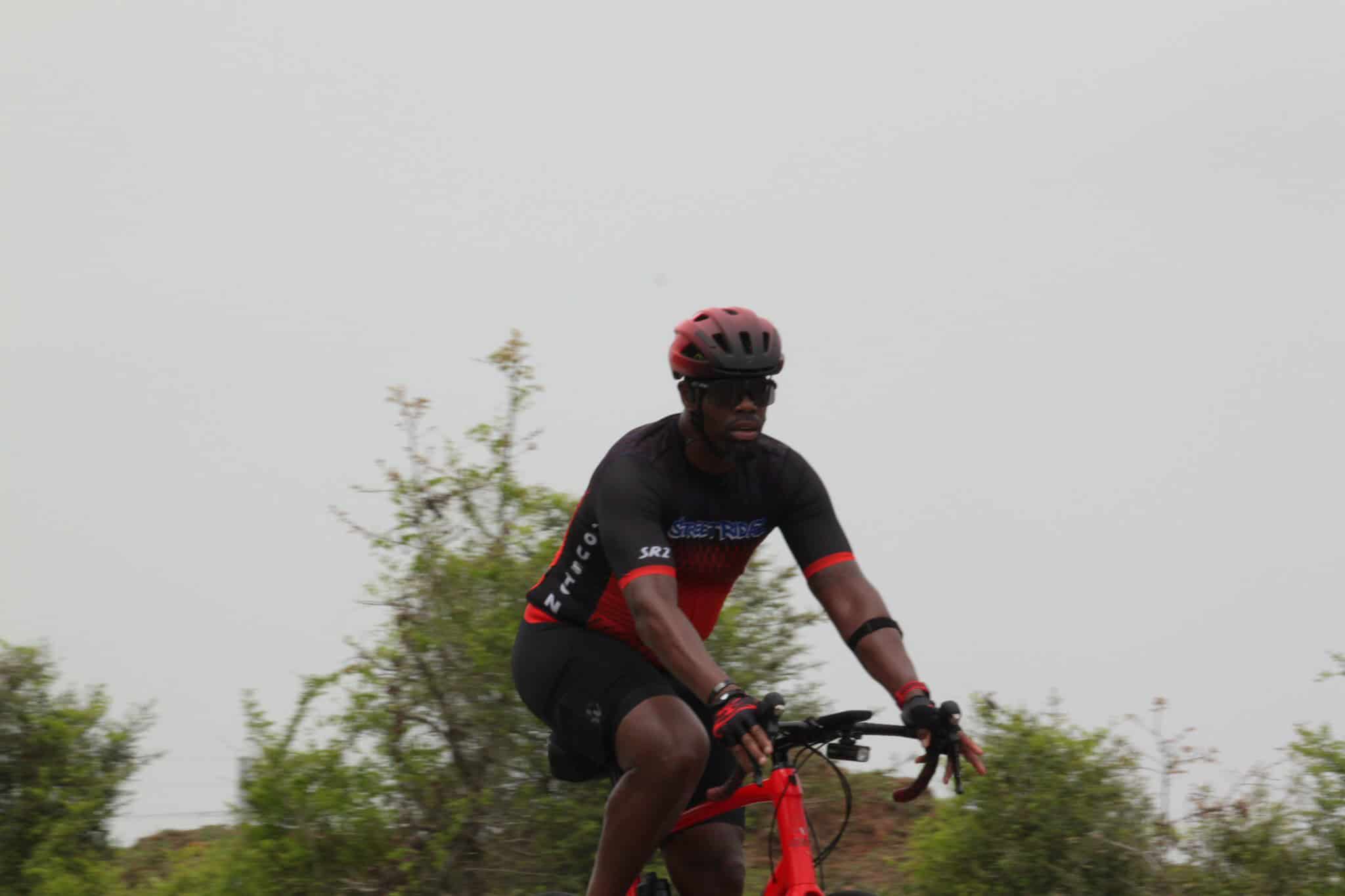 Vibrant cyclist riding a red bike on scenic outdoor trail with greenery, promoting Bluebonnet Express bike tours.