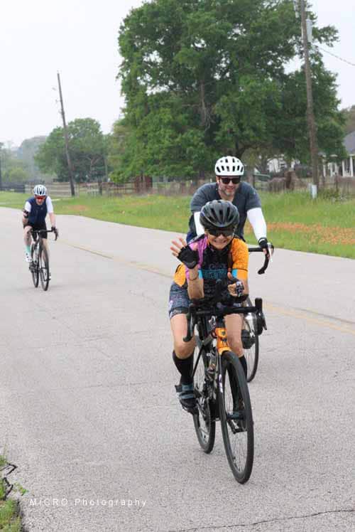 Brightly dressed children and adult riding bikes together on a scenic rural road, enjoying outdoor cycling activity.