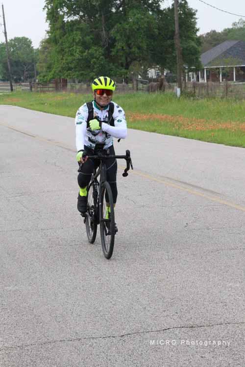 Bright yellow helmet and gloves worn by cyclist on scenic rural road.