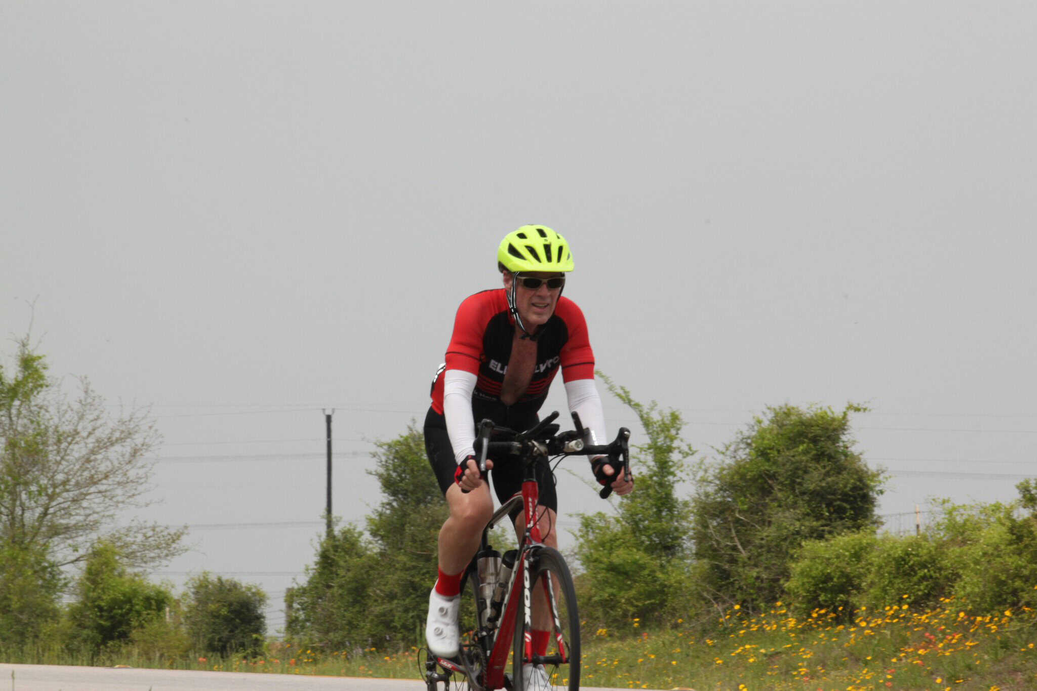 Bright yellow bike helmet and red cycling jersey riding on scenic outdoor bike trail.