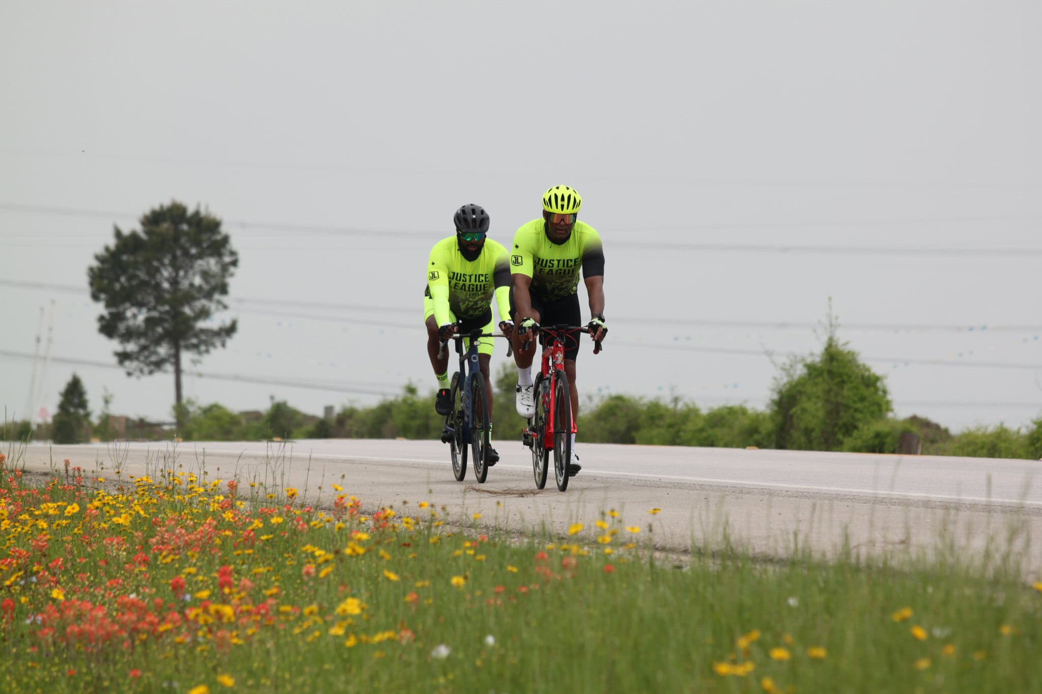 Bright yellow cycling jerseys with "Justice League" logo on bike ride.