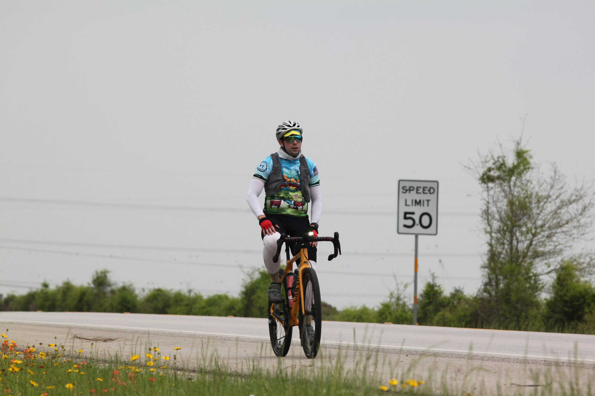 Cyclist riding on the road with a speed limit sign, promoting outdoor biking adventures and eco-friendly transportation.