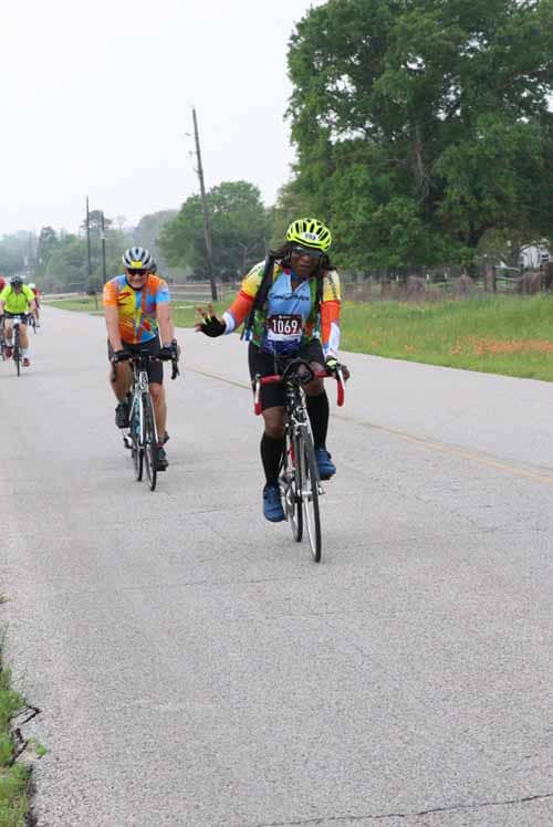 Brightly dressed cyclists participating in the Bluebonnet Express charity ride on a rural road.