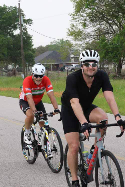 Brightly dressed cyclists riding on a paved road during daytime, enjoying a cycling tour in Texas.