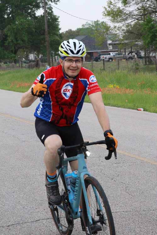 Happy cyclist riding a blue bike on the road, showcasing outdoor biking and fitness.