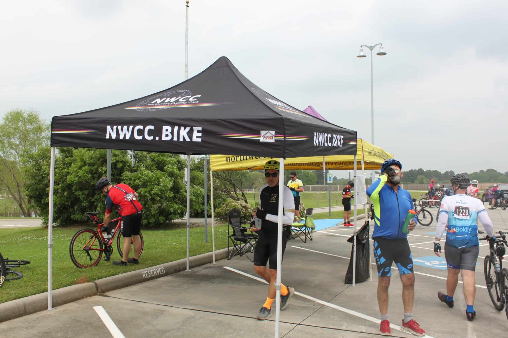 High-angle view of cyclists at Bluebonnet Express event under NWCC.BIKE tent, promoting cycling events and community engagement.