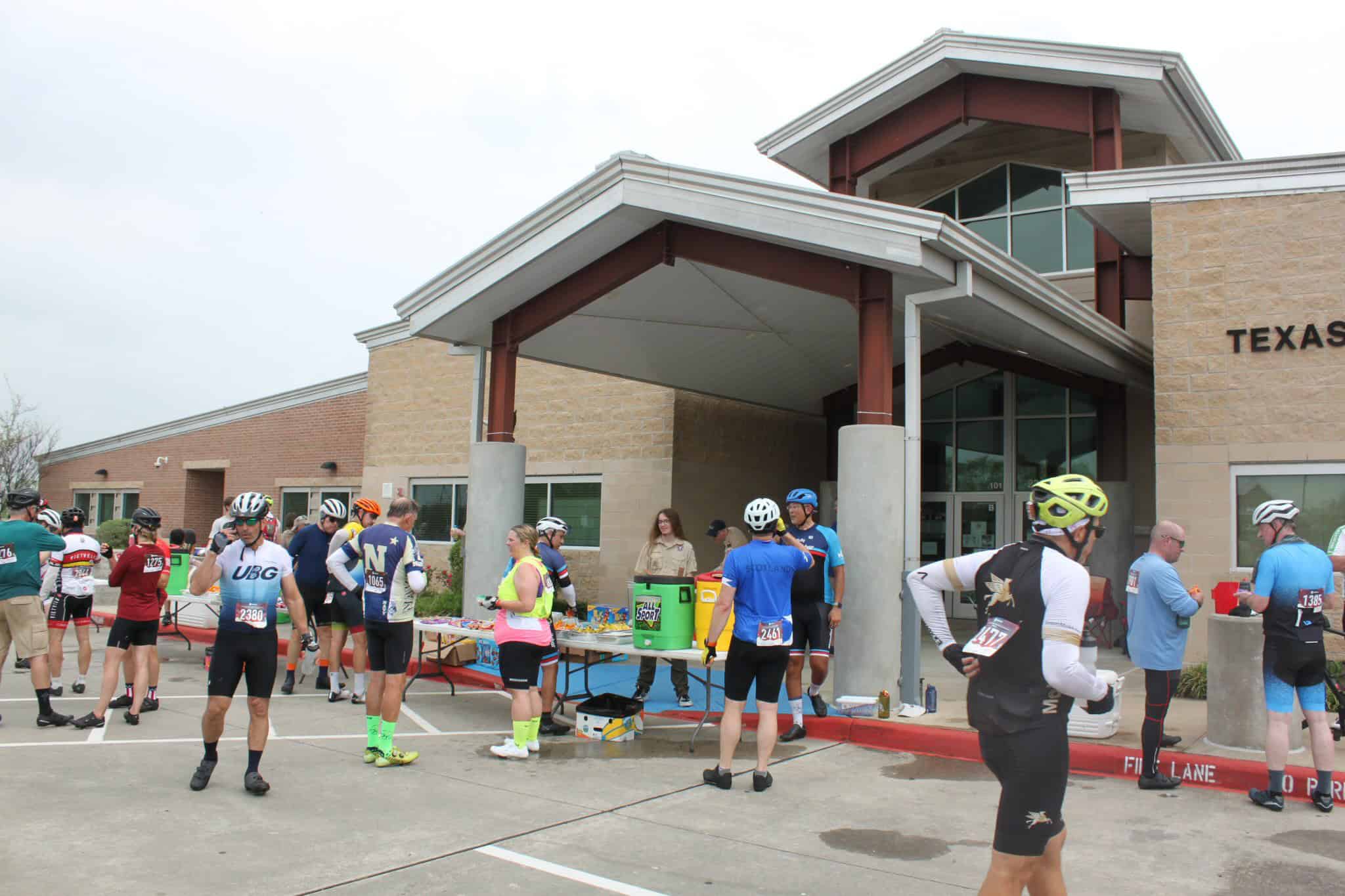 Cyclists gather at Bluebonnet Express event outside Texas high school for race registration and refreshments.