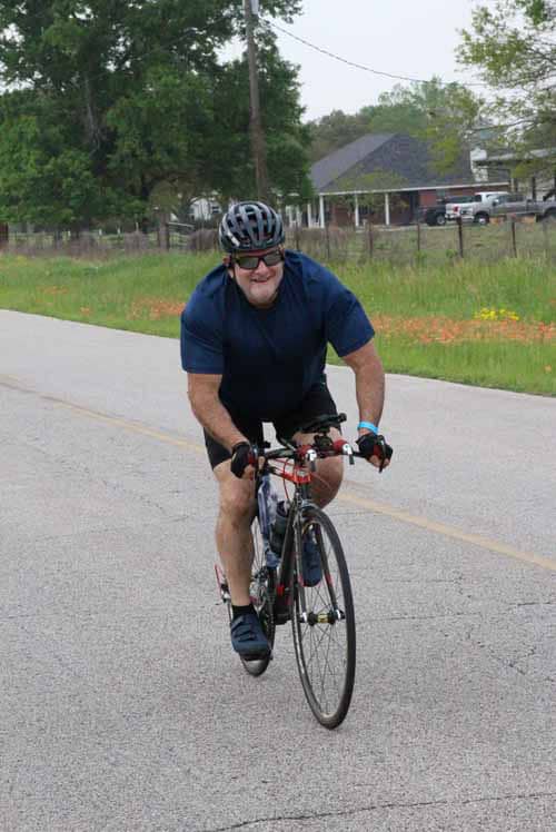 1. Man riding a bicycle on a rural road, wearing helmet and sunglasses.
